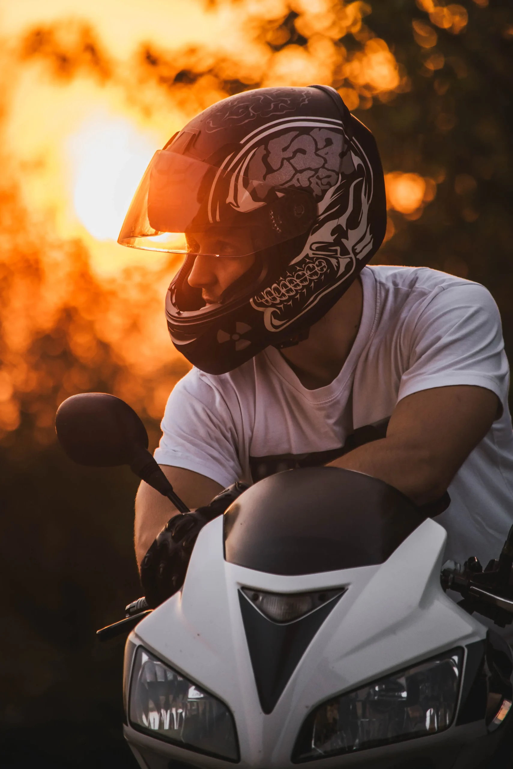 Mężczyzna w kasku siedzący na motocyklu i wpatrujący się w dal.