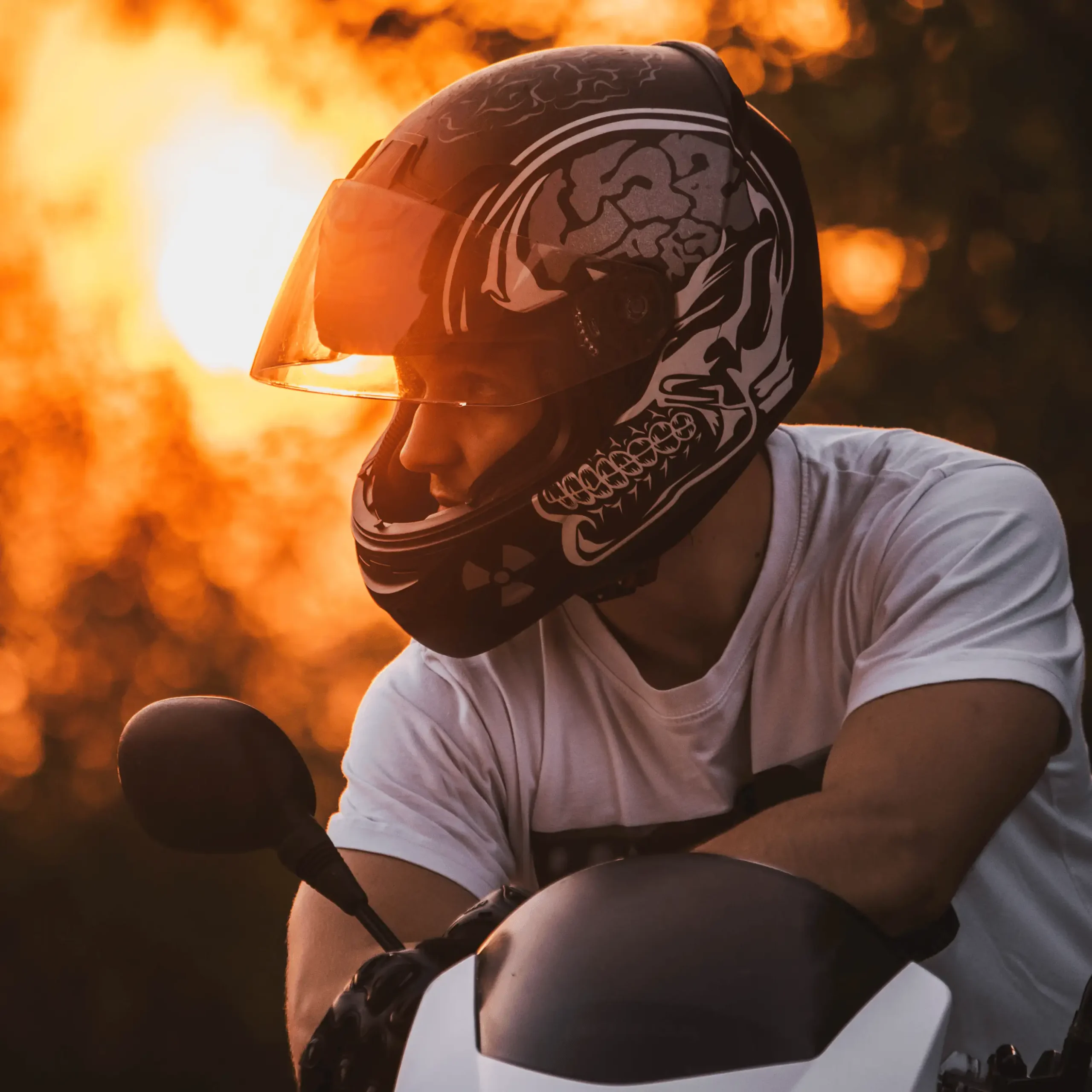 Mężczyzna w kasku siedzący na motocyklu i wpatrujący się w dal.