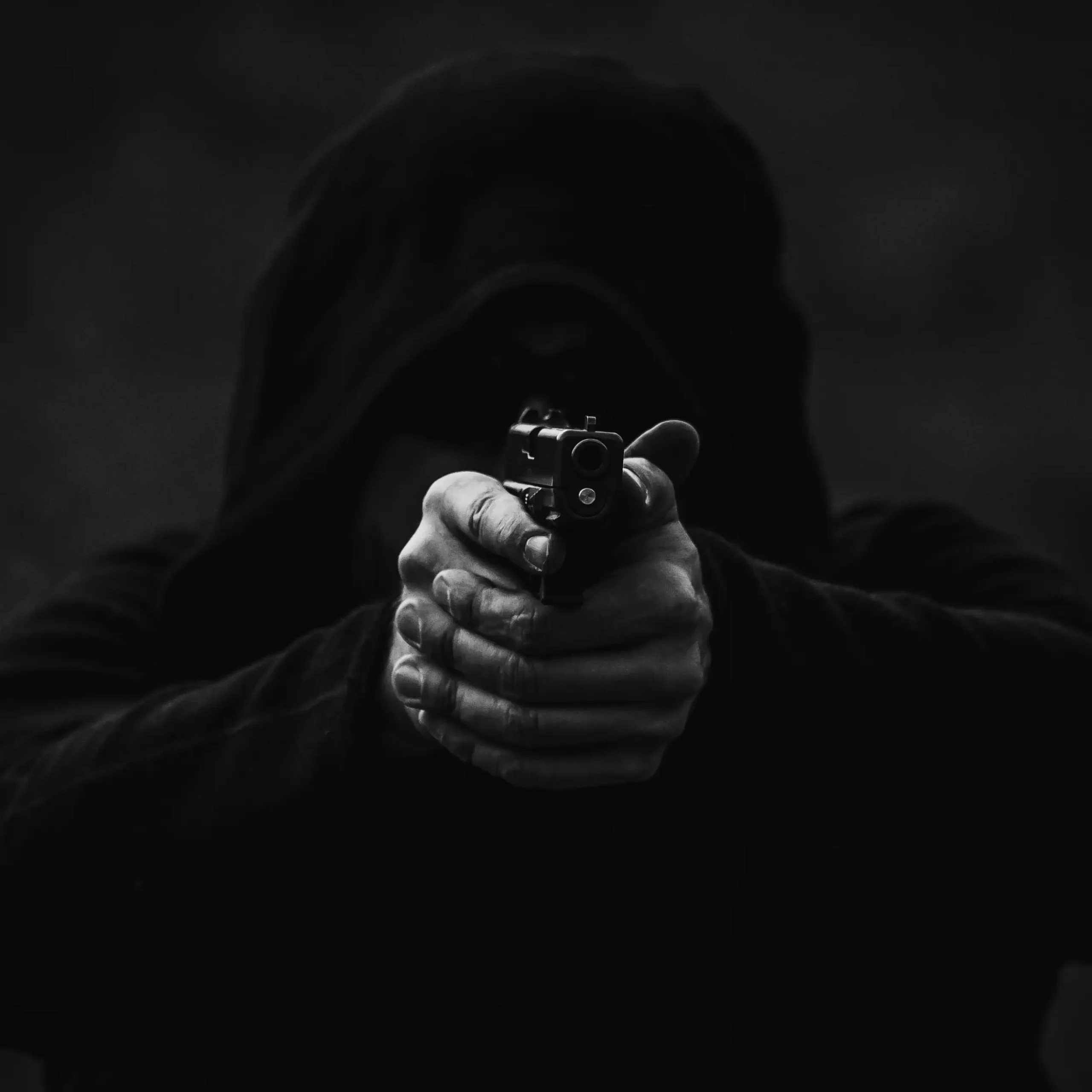 Mężczyzna trzymający pistolet mierząc do obiektywu.